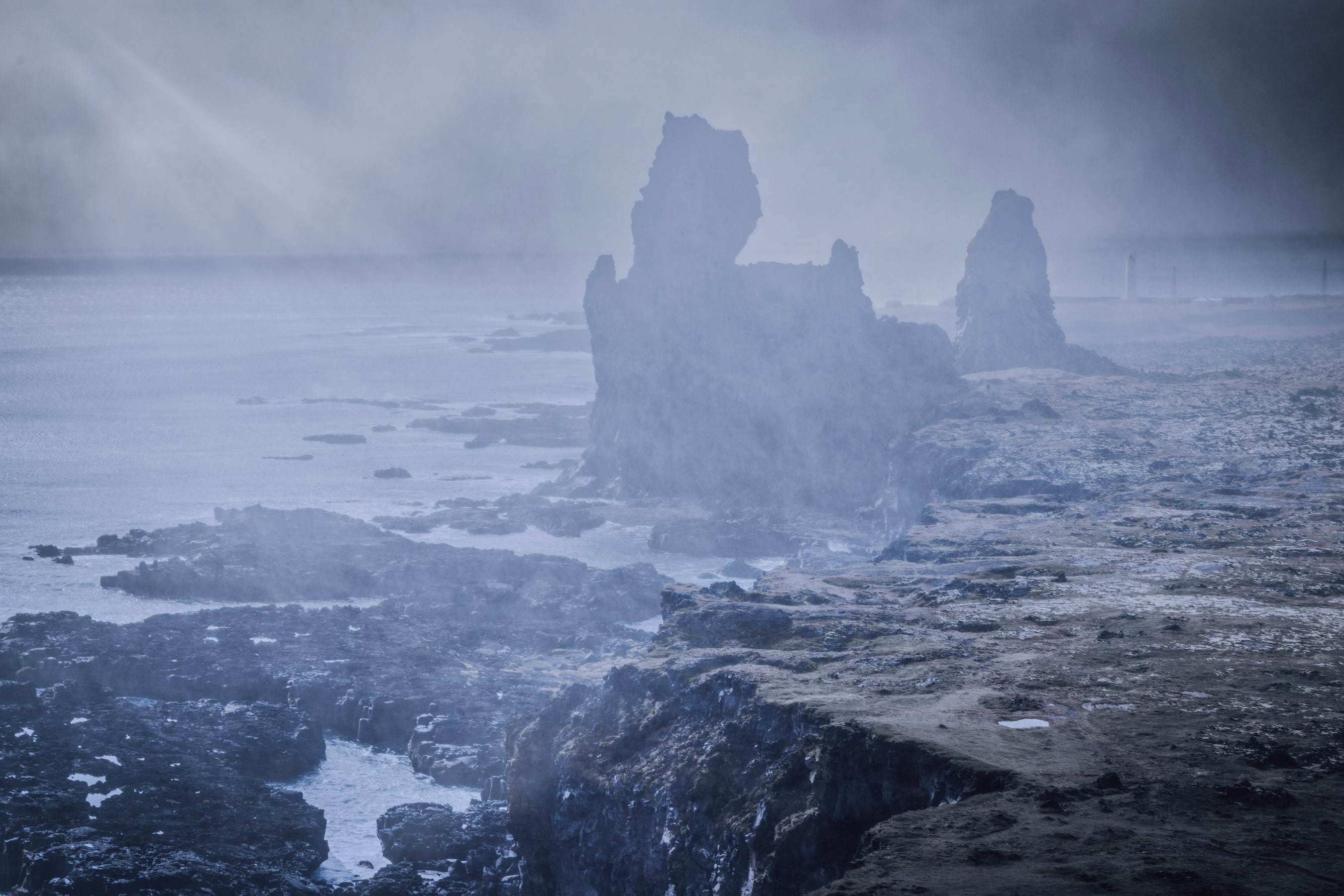 Sea stacks on an Icelandic headland half hidden in wind-driven spray and mist