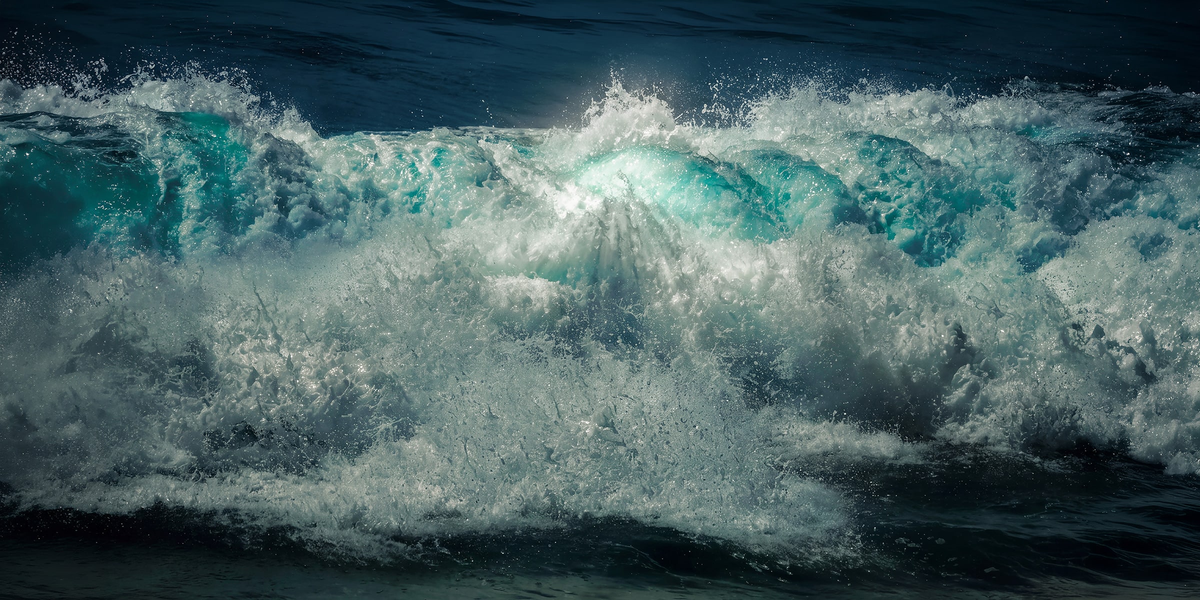 A powerful breaking wave fills the frame off Cabo San Lucas, Mexico, luminous turquoise water bursting through deep midnight-blue ocean and exploding whitewater.